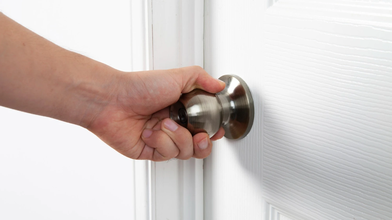 a hand tries to spin a door knob attached to a white door